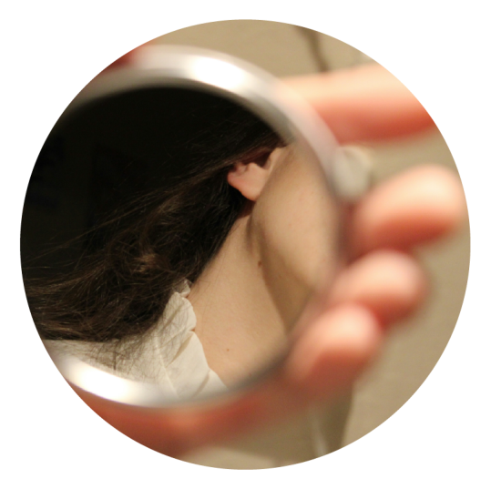 a small hand mirror being held up by a hand with a person's neck in the mirror to show who they want to become