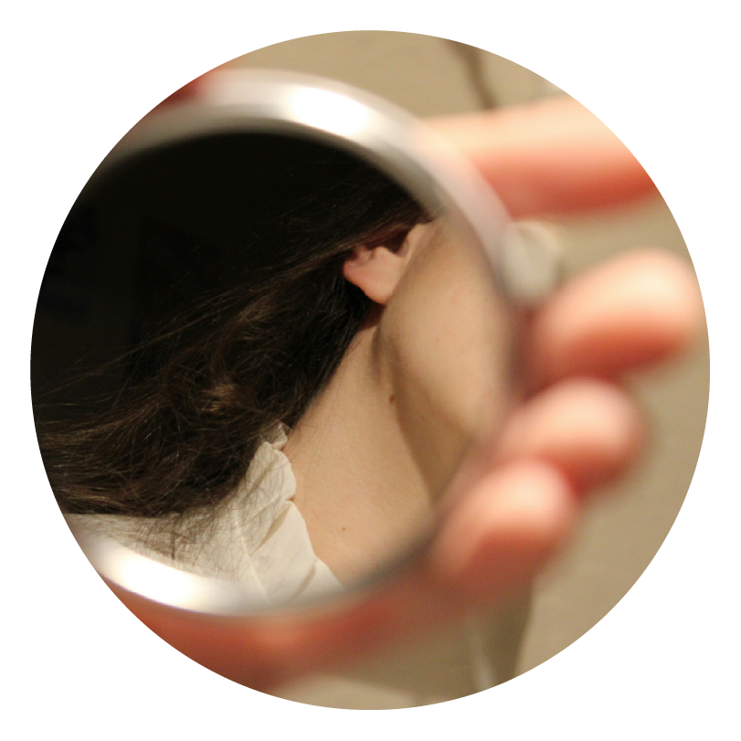 a small hand mirror being held up by a hand with a person's neck in the mirror to show who they want to become
