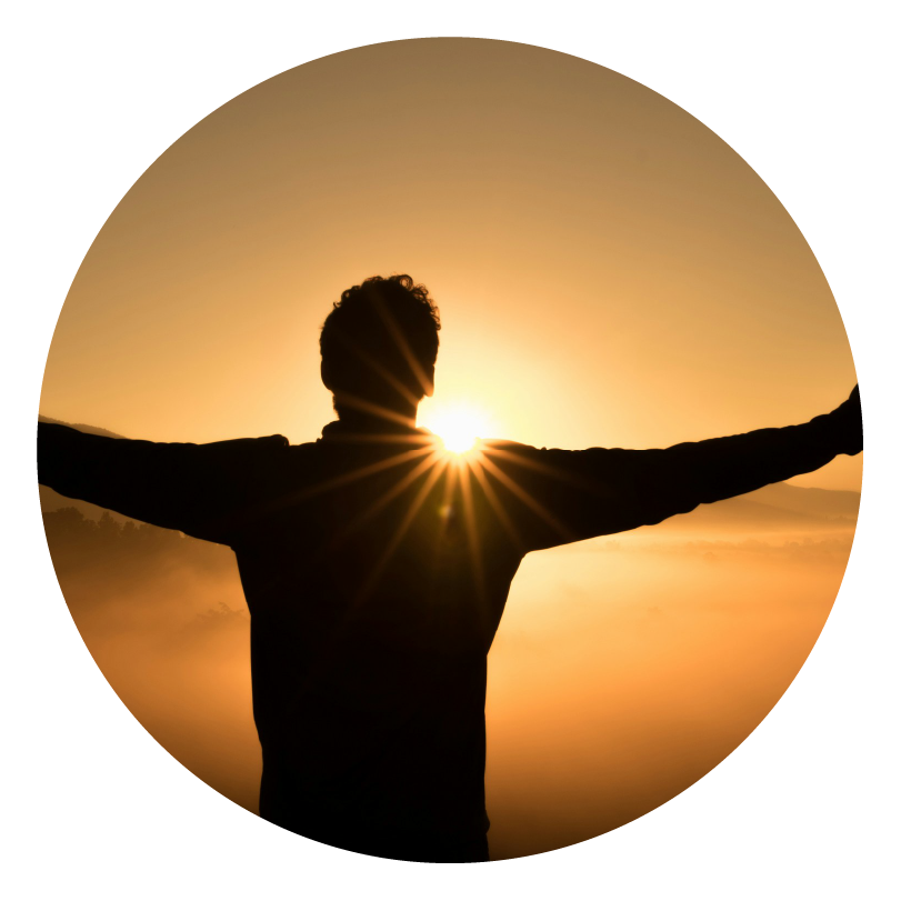 golden sunset with a man with his arms outstretched in the foreground showing success