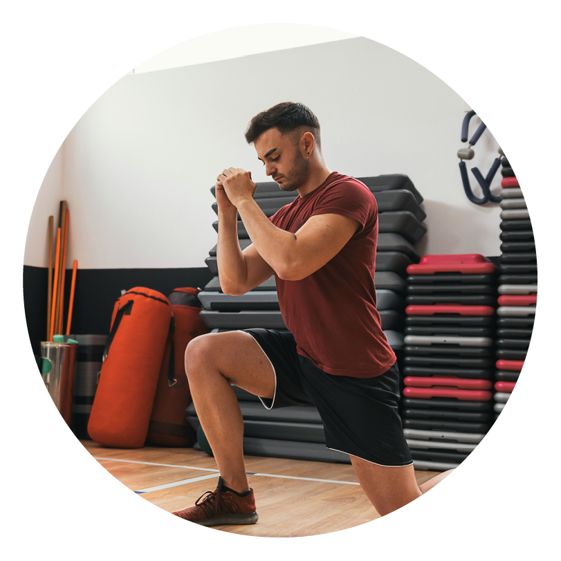 man in a red t-shirt doing a lunge in the gym to show determination
